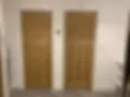 Two matching high-quality natural wood internal doors with polished brass handles in a hallway