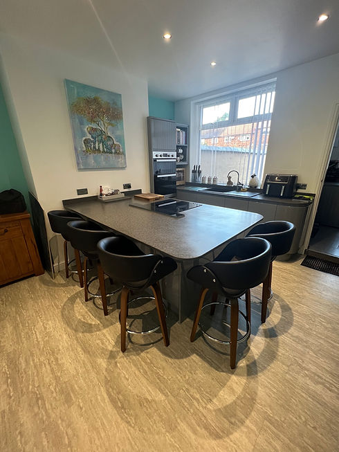 Large dark grey kitchen island with matching leather bar stools and wooden floor