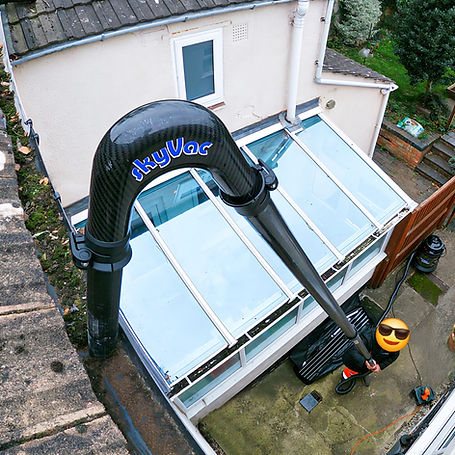 A high-reach SkyVac system being used to clean a gutter over a glass conservatory roof