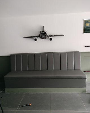 Grey upholstered bench seating with vertical panelled backrest in a modern interior