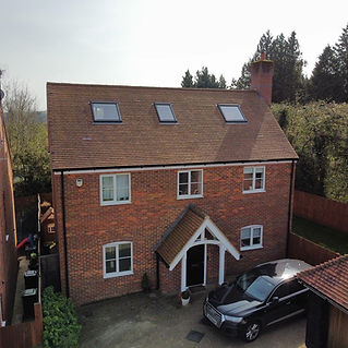 Aerial view of a house with a flat-roofed dormer and a black car parked out front