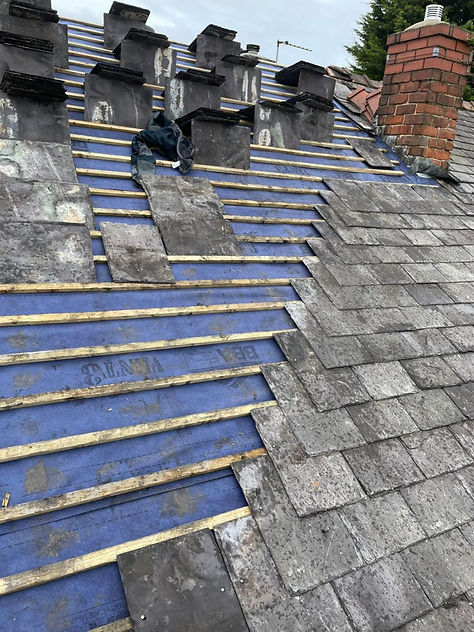 Close up of new grey roof tiles being laid on a wooden batten frame