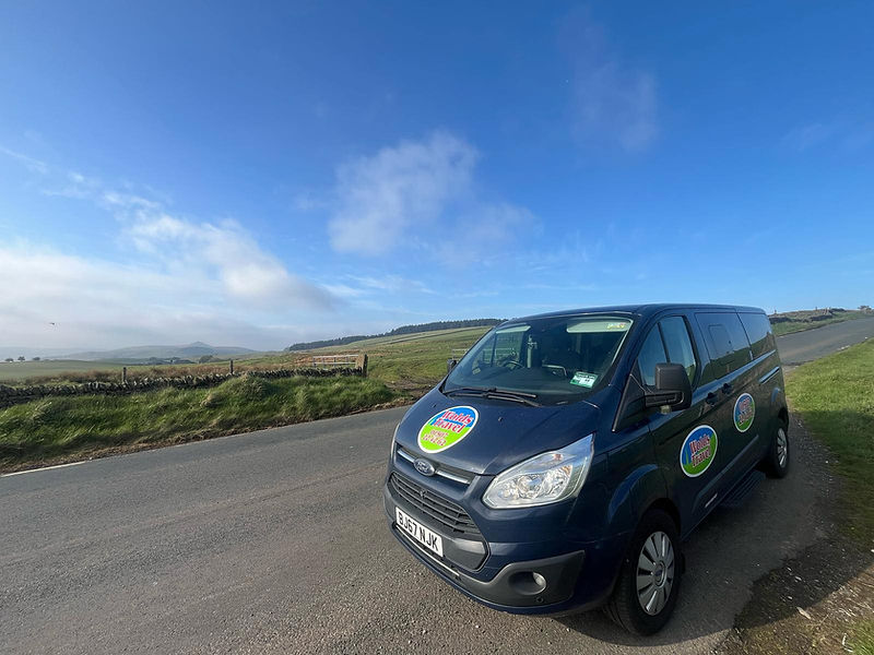 A blue van with company branding decals parked on the road