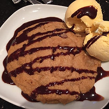 A chocolate sauce is paired with two scoops of vanilla ice cream on a white plate