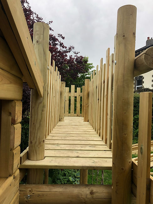 Looking through a wooden play bridge featuring vertical safety rope sides