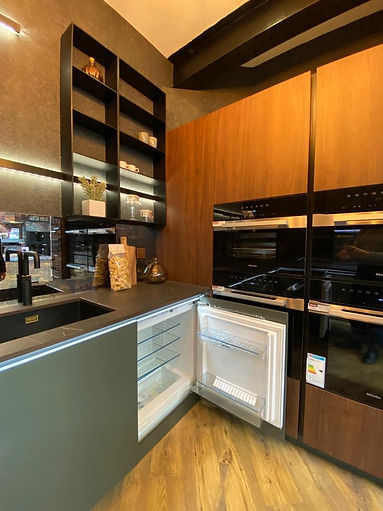 Bespoke kitchen display with dark wood cabinets and integrated appliances