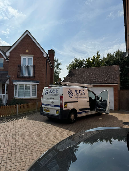 White service van parked on a residential driveway in front of a red brick house under a blue sky