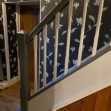 staircase with dark floral wallpaper and white spindles