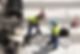Two drainage contractors in safety gear discussing a site plan next to an open manhole