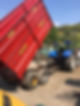 Blue tractor with large tires is attached to a red tipped trailer labeled Marshall