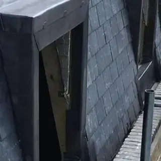 Grey slate mansard roof featuring two recessed window openings with lead flashing