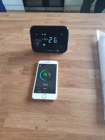 Modern digital thermostat and smartphone showing remote heating control interface