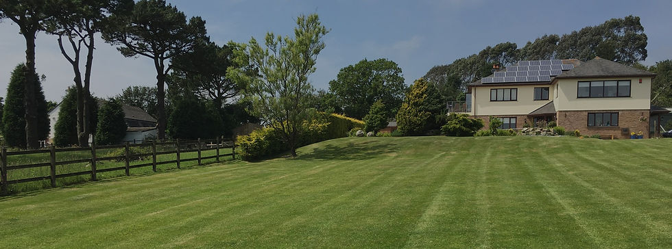 Large manicured lawn and garden in front of a modern house with solar panels