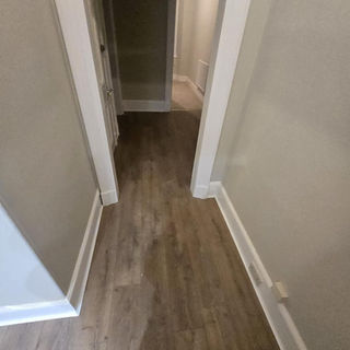 Textured grey wood effect flooring installed in a narrow hallway with white trim