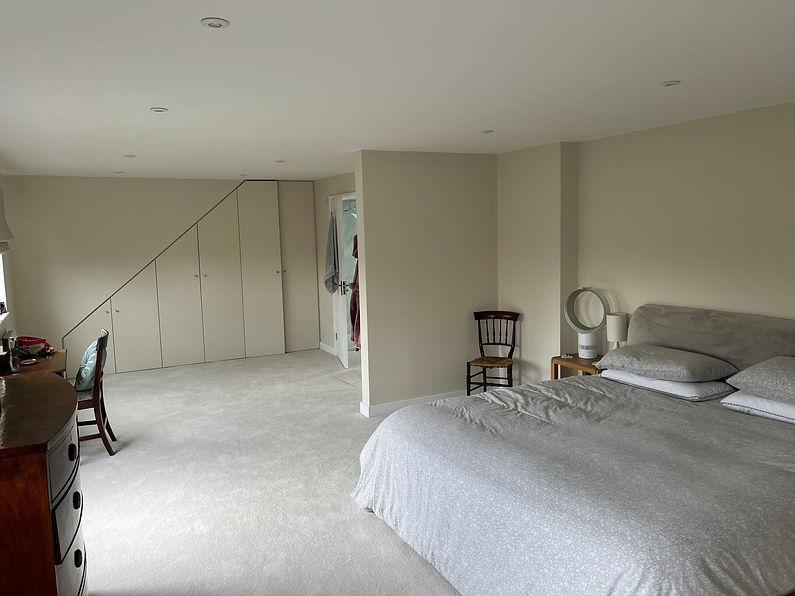 Completed attic bedroom featuring custom fitted wardrobes built into the sloping eaves