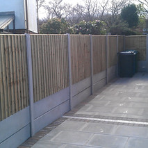 Vertical timber fencing with concrete posts and gravel boards next to a paved side access area