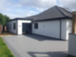 White house extension with a grey composite deck patio and dark framed windows on a sunny day