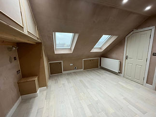Empty attic room undergoing conversion with twin skylights and exposed plasterboard