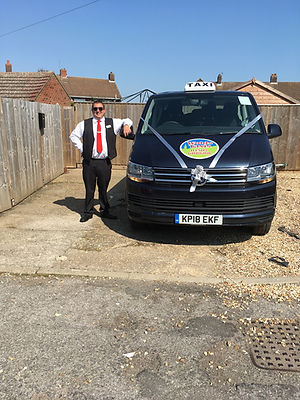 A smiling man standing next to a dark blue van with the company branding
