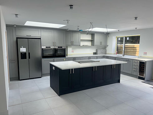 Modern grey kitchen with large island, built-in ovens and skylights above