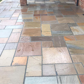 Light grey and beige natural stone paving stones laid out for a spacious outdoor patio