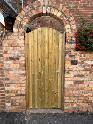 Custom made timber garden gate perfectly fitted into a decorative brick archway