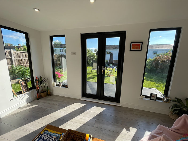 Modern garden room interior with large black framed windows and French doors facing garden