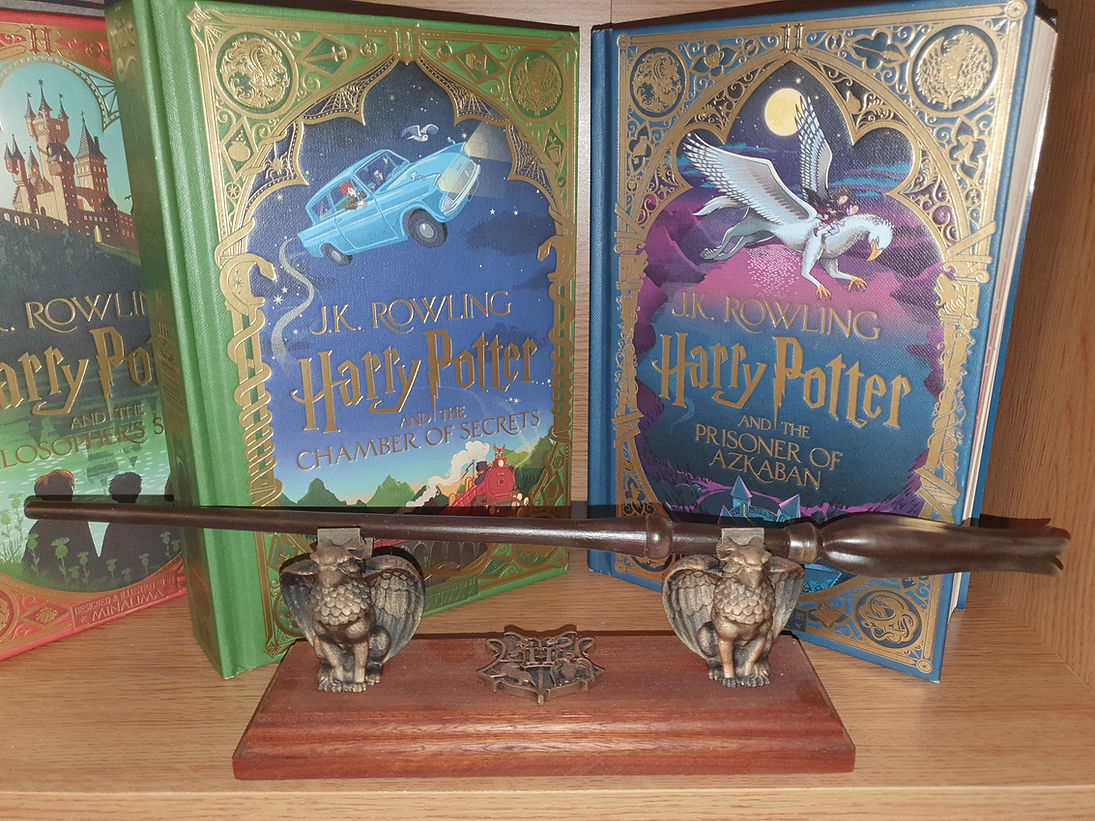 Three illustrated Harry Potter books with ornate covers are displayed on a shelf