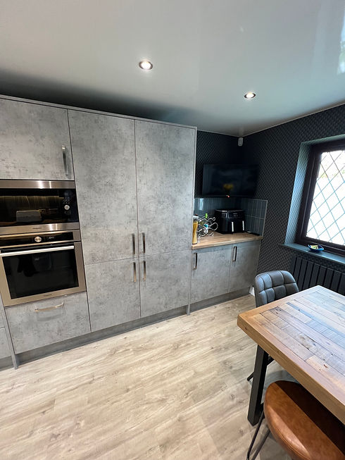 Modern handleless grey concrete effect kitchen cabinets with integrated double oven