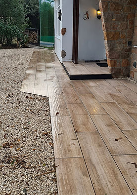 Wet wooden tiles lead to a cozy entrance with a stone wall and lantern