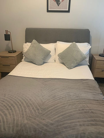 A neatly made bed with a grey headboard