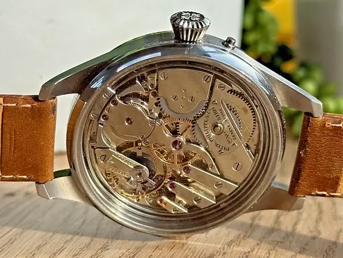 Watch mechanical movement, showcasing gears and springs in a gold-toned finish