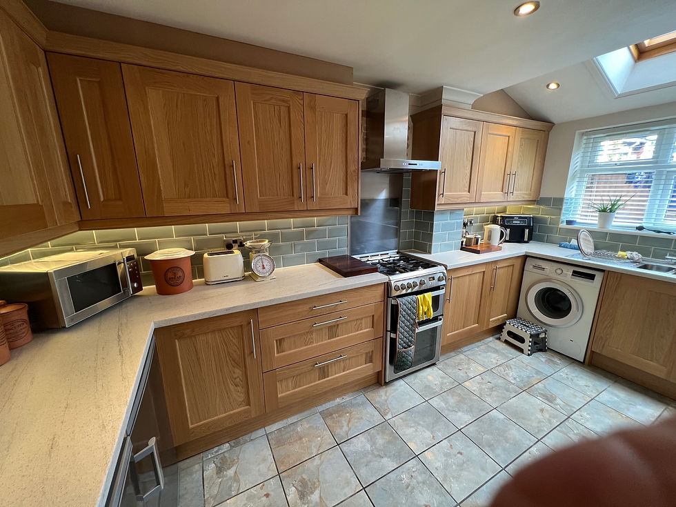 L-shaped light oak fitted kitchen with granite worktops and integrated washing machine