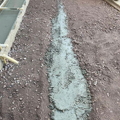 Freshly poured concrete foundation trench in a garden