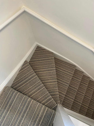 Close-up of striped carpet fitted on a winder staircase