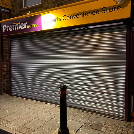 A silver metal roller shutter on a convenience store
