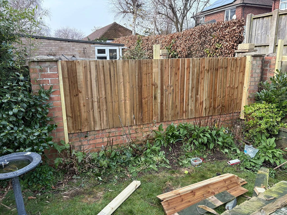 A partially completed wooden fence section in a backyard