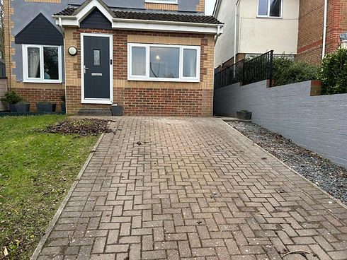 house with a dark blue door, large front window, and a sloping driveway