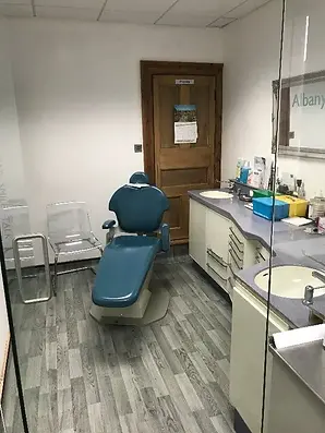 A treatment room inside the dental centre with a blue examination chair and white cabinets
