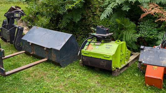 Various heavy-duty machinery attachments sitting on grass