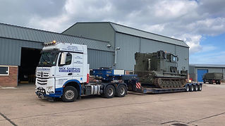Military vehicle on trailer in industrial area