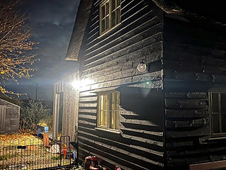 A dark wooden house at night, illuminated by an outdoor light