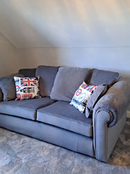 Grey two seater sofa with London themed cushions in a carpeted room