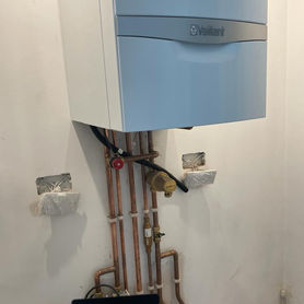 Close up of a newly fitted Vaillant boiler with complex copper pipework connections underneath