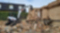 White mini excavator dismantling a brick wall
