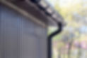 Close up of a black downpipe and guttering system on a modern metal clad building