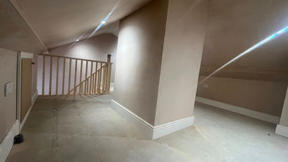 Spacious loft landing with freshly plastered walls, a central support column, and a wooden safety banister