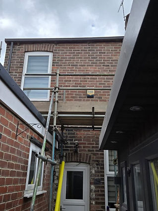 Narrow brick alley with scaffolding above a white door