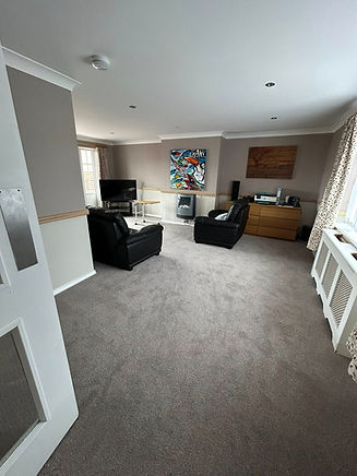 Interior view of a modern living room featuring beige carpet white walls and dark furniture