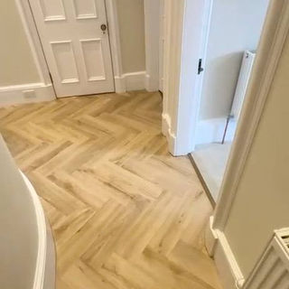 Light ash herringbone LVT flooring in a hallway with traditional white doors